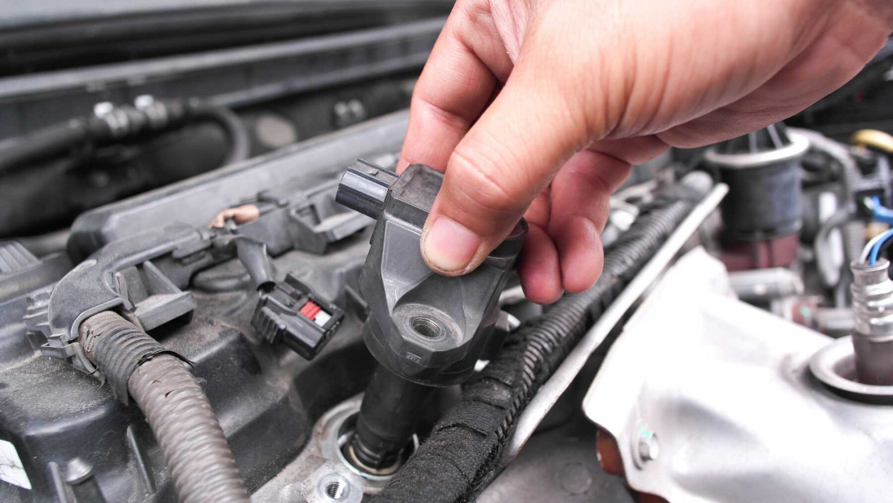 mechanic diagnosing ignition coil failure symptoms in a car engine