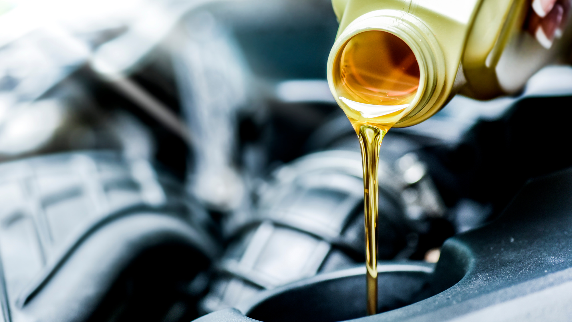 Mechanic pouring full synthetic motor oil into car engine to show differences between synthetic and conventional oil.