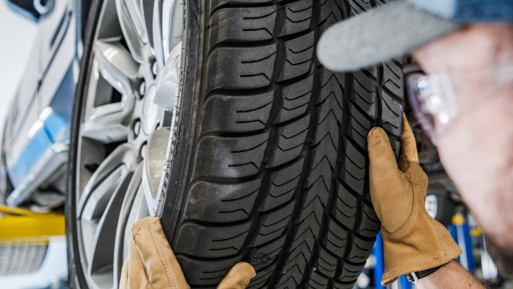 Mechanic inspecting a car wheel to diagnose tire wobble at Heart Certified Auto Care.