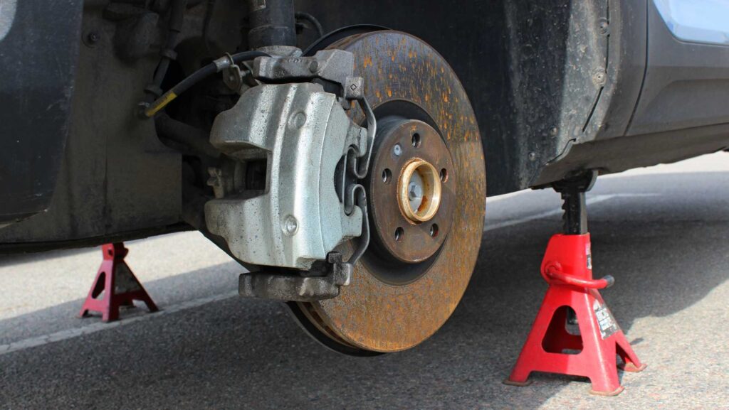 Technician inspecting worn brake pads at HEART Certified Auto Care in Evanston