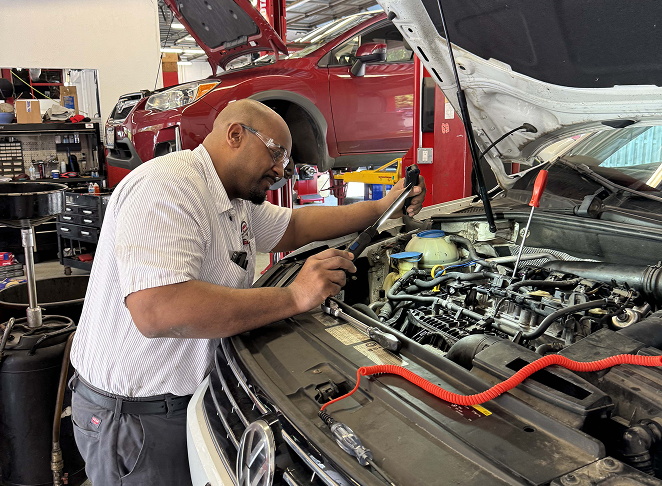 Technician inspecting a vehicle engine bay during a service appointment